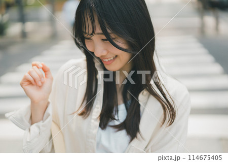 横断歩道を渡る若い女性 114675405