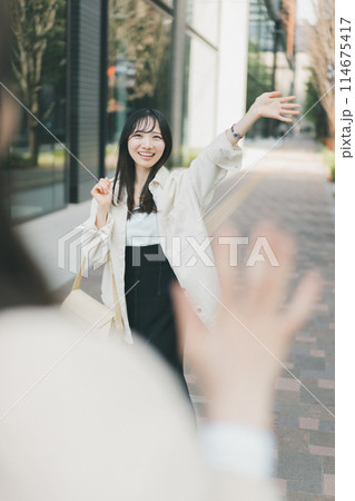待ち合わせ場所で待ち合わせ相手に手を振る女性 114675417