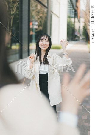 待ち合わせ場所で待ち合わせ相手に手を振る女性 114675419