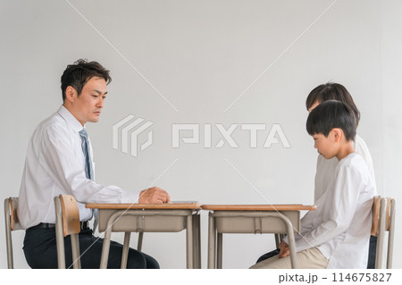学校の教室で男性教師と三者面談・個人面談する悩む親子（小学生・男の子） 114675827