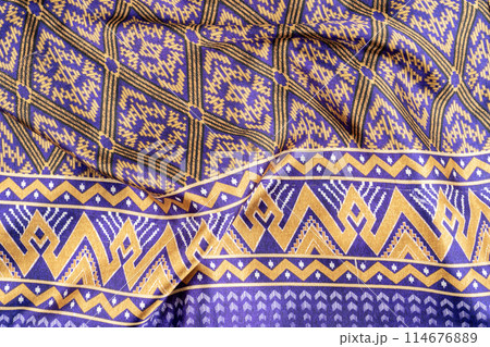Thai Northeast Sarong, Handwoven Mudmee or Ikat silk fabric in blue pattern in vintage tone background. Thai Northeast Sarong, Handwoven Mudmee or Ikat silk fabric in blue pattern in vintage tone background. 114676889