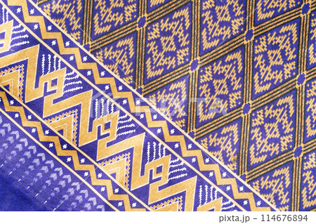 Thai Northeast Sarong, Handwoven Mudmee or Ikat silk fabric in blue pattern in vintage tone background. 114676894
