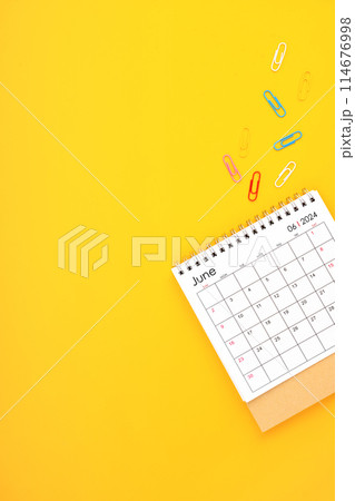 June 2024 desk calendar and paper clips on yellow color background. 114676998