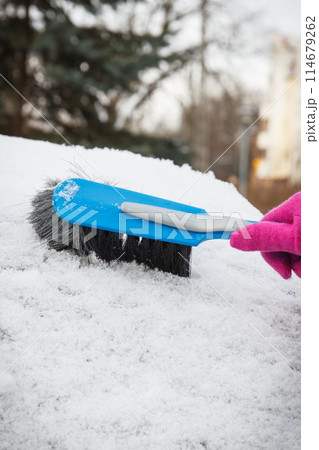 Hand of woman using brush and remove snow from car and windscreen 114679262