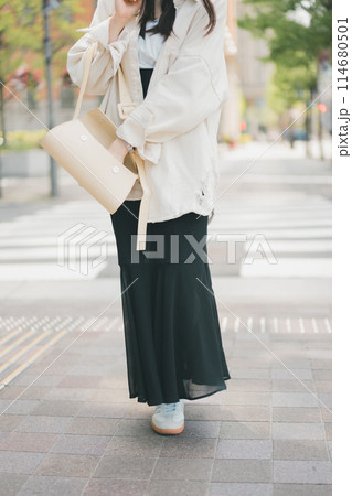 バッグの中から何かを取り出す街を歩く若い女性 バッグの中から何かを取り出す街を歩く若い女性 114680501