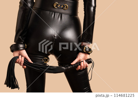Beautiful dominant mistress woman in latex catsuit posing with riding crop Beautiful dominant mistress woman in latex catsuit posing with riding crop 114681225