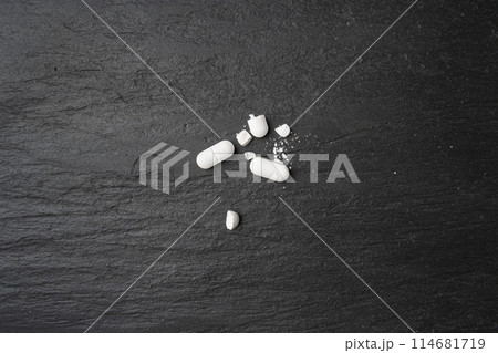 Broken Pills, Crushed Aspirin, Split Tablet, Broken Pill Capsules, Crumbling White Drugs on Black 114681719