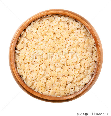 Stelle or stelline, pastina variety and Italian soup pasta in a wooden bowl. Uncooked durum wheat semolina minute pasta. Tiny stars with a hole in the center. Mainly used for soups and some salads. 114684484