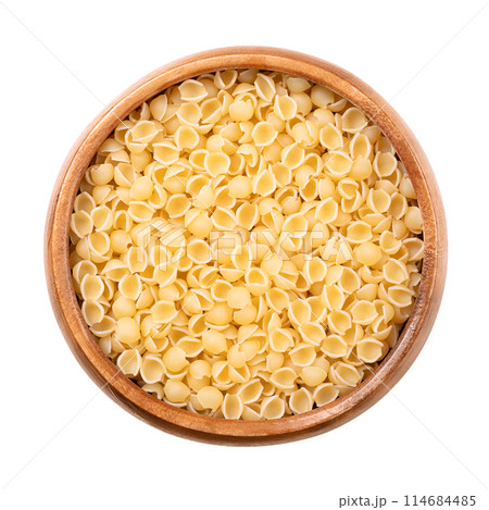 Perline or conchiglie, pastina variety and Italian soup pasta in a wooden bowl. Tiny, round, shell shaped, uncooked durum wheat semolina minute pasta. Mainly used for soups and in some types of salad. 114684485