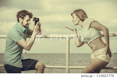 Young couple in love is taking photos on sea pier. Young couple in love is taking photos on sea pier. 114687776