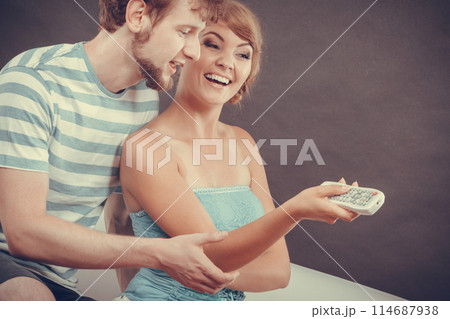 Happy couple on sofa with TV remote 114687938