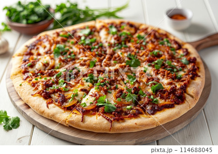 Freshly baked pizza topped with caramelized onions, mozzarella, and cilantro on a wooden board Freshly baked pizza topped with caramelized onions, mozzarella, and cilantro on a wooden board 114688045