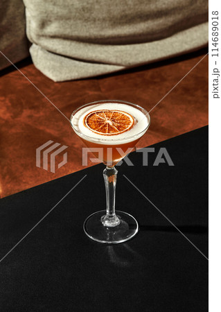 Glass of frothy almond sour cocktail with dried grapefruit slice 114689018