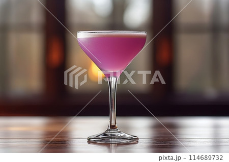Elegant purple Aviation cocktail in a glass on a table, with a warm, blurred background 114689732
