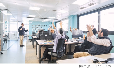 Businesspeople applauding as manager shares good news with them in office 114690729