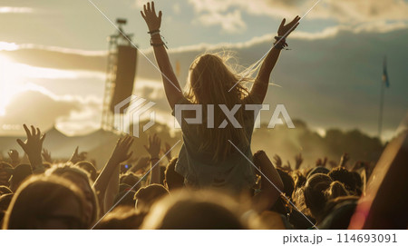 a person sitting atop someones shoulders, their hands reaching for the sky at a summer music festival a person sitting atop someones shoulders, their hands reaching for the sky at a summer music festival 114693091