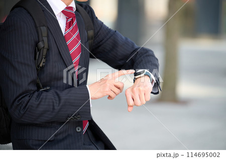 スマートウォッチを見るスーツ姿のビジネスマン 114695002