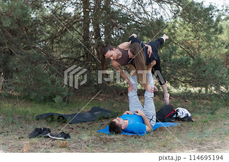Thre people standing in an elaborate acro yoga pose. Thre people standing in an elaborate acro yoga pose. 114695194