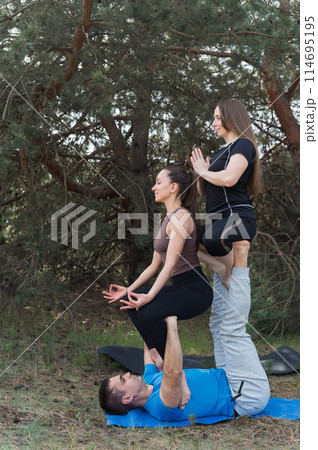 Thre people standing in an elaborate acro yoga pose. Thre people standing in an elaborate acro yoga pose. 114695195