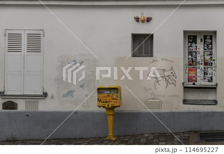 Shutters and windows with small peephole on old wall of a ground floor residence and Post box. 114695227