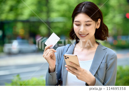 スマホとカードを持つ若いビジネスウーマン スマホとカードを持つ若いビジネスウーマン 114695358