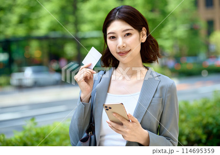 スマホとカードを持つ若いビジネスウーマン 114695359