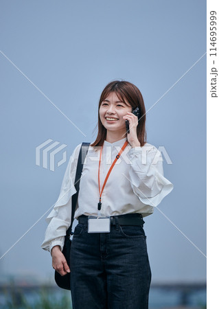 スマホで電話をしながら歩く若い女性 114695999