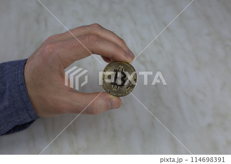 Man holding physical bitcoin, cryptocurrency gold coin, popular risky investment concept 114698391