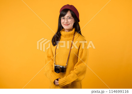 In her cheerful studio, a young Asian woman, wearing a yellow sweater and red beret, snaps pictures with her camera, embracing the joy of photography. In her cheerful studio, a young Asian woman, wearing a yellow sweater and red beret, snaps pictures with her camera, embracing the joy of photography. 114699116