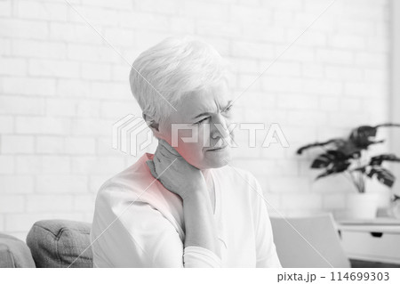 Mature woman suffering from backache at home, massaging neck with hand, feeling exhausted, empty space 114699303