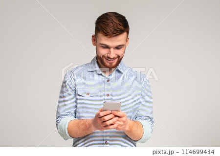 Young man absorbedly text messaging on his cellphone, panorama, free space Young man absorbedly text messaging on his cellphone, panorama, free space 114699434