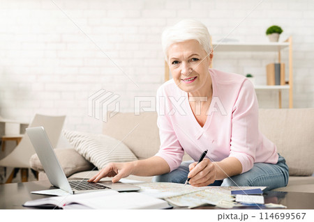 Active senior lady planning trip, choosing travel route on map at home, free space 114699567