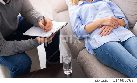 At the psychologist. Young woman lying on couch while doctor making notes, panorama At the psychologist. Young woman lying on couch while doctor making notes, panorama 114699765