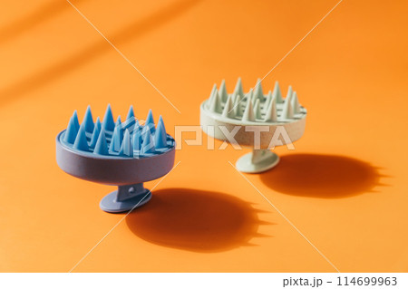 Blue and green massager for the scalp on an orange background 114699963