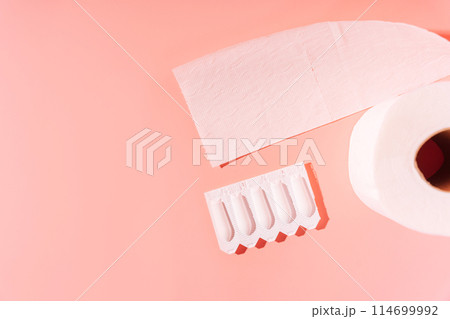 Rectal candles in packaging and toilet paper on a pink background 114699992