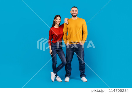 A man and a woman are standing side by side, looking in the same direction. They appear to be engaged in conversation or observing something in front of them. 114700284