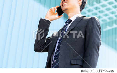 スマホで通話をする笑顔の男性ビジネスマン 114700330