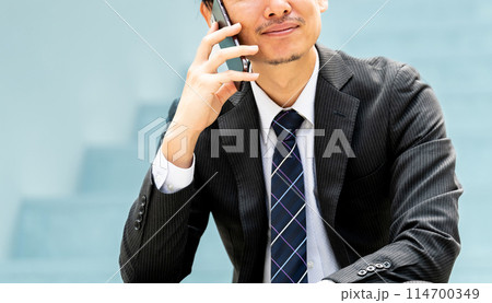スマホで通話をする笑顔の男性ビジネスマン 114700349