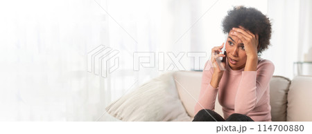 A stressed african american woman looks worried while on the phone, with ample copy space to the left, fitting for web-banner A stressed african american woman looks worried while on the phone, with ample copy space to the left, fitting for web-banner 114700880