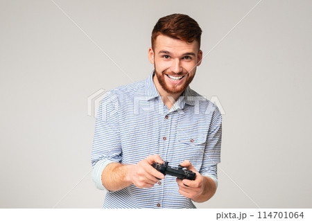Excited millennial guy playing video games with jpystick and smiling, panorama, free space Excited millennial guy playing video games with jpystick and smiling, panorama, free space 114701064
