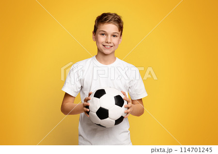Favorite sport. Cute boy holding soccer ball, smiling on orange studio background, panorama with free space Favorite sport. Cute boy holding soccer ball, smiling on orange studio background, panorama with free space 114701245