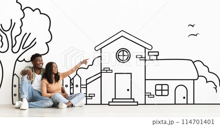 Joyful African American couple planning their dream home against a hand-drawn house sketch on white wall Joyful African American couple planning their dream home against a hand-drawn house sketch on white wall 114701401