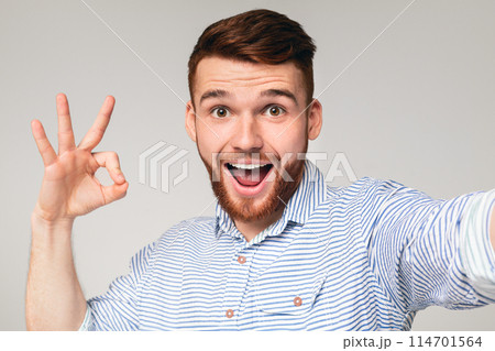 Happy millennial guy showing OK sign on camera and making selfie, panorama 114701564