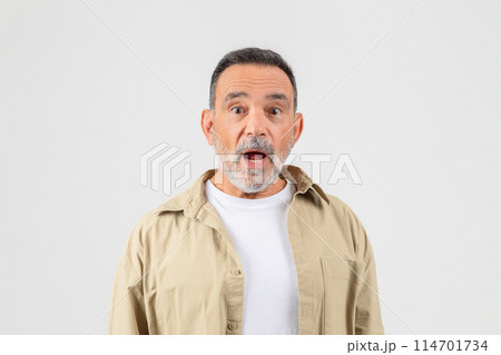 A senior man with a look of surprise on his face, eyebrows raised, mouth slightly agape. His eyes are wide, indicating shock or astonishment. He appears taken aback by something unexpected. 114701734