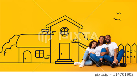 Excited black family of three father mother and teen daughter sitting on floor, looking at illustrated house of their dreams over yellow wall background. 114701902