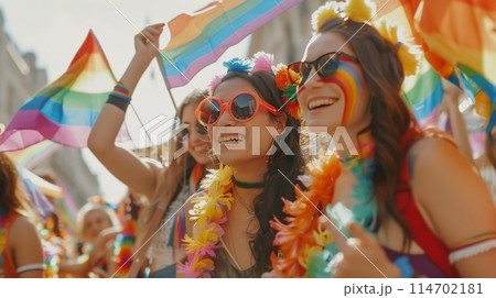 Crowd celebrating with rainbow flags at a public event 114702181