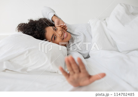 A woman is seen laying in bed with a white blanket covering her body, stretching. She appears to be resting comfortably in a cozy setting. A woman is seen laying in bed with a white blanket covering her body, stretching. She appears to be resting comfortably in a cozy setting. 114702485