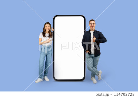 Young man and woman standing next to an enormous mobile mockup screen copy space for advertisement, studio background Young man and woman standing next to an enormous mobile mockup screen copy space for advertisement, studio background 114702728