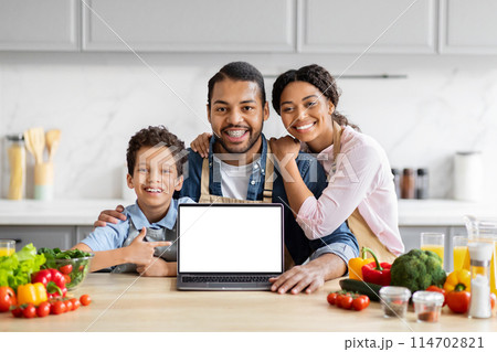 Smiling loving black family showing laptop with white blank screen, cooking together at kitchen, mockup copy space Smiling loving black family showing laptop with white blank screen, cooking together at kitchen, mockup copy space 114702821