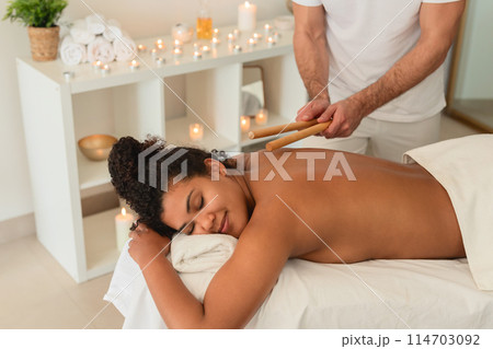 A spa therapist utilizes singing bowls for a sound therapy session with a peaceful African American lady, enhancing the holistic experience for people A spa therapist utilizes singing bowls for a sound therapy session with a peaceful African American lady, enhancing the holistic experience for people 114703092